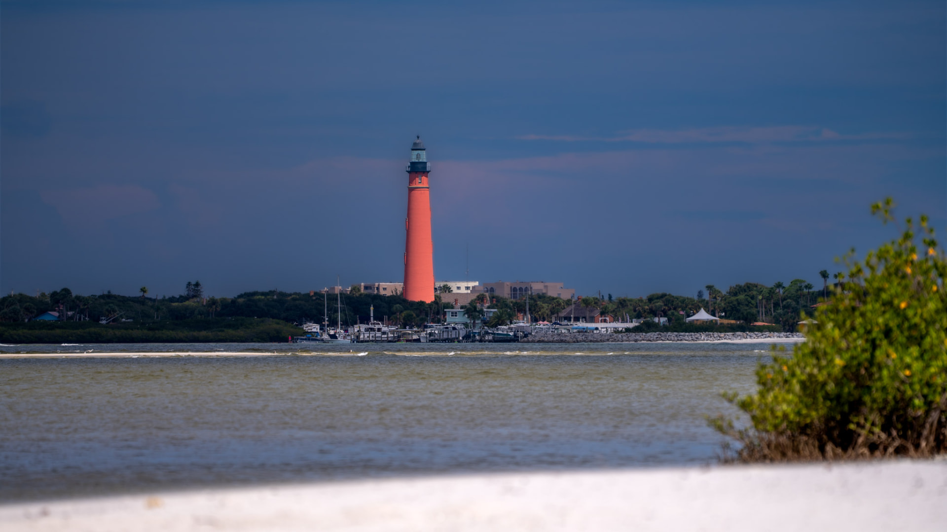 Ponce Inlet Lighthouse rising in vivid orange against a deep blue sky above the Intracoastal Waterway