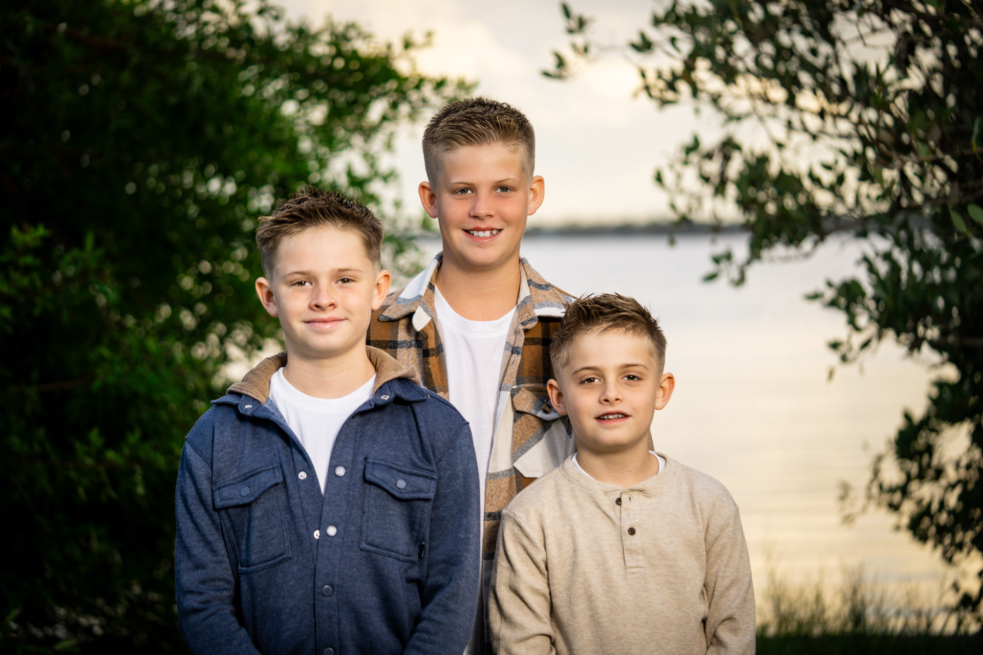 Three brothers standing together by a lake in soft evening light